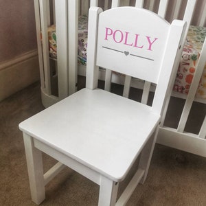 Pu&ograve; includere: Sedia di legno bianca per bambini con schienale arrotondato. Lo schienale della sedia &egrave; dipinto con il nome "POLLY" in lettere rosa con un cuore grigio sotto.