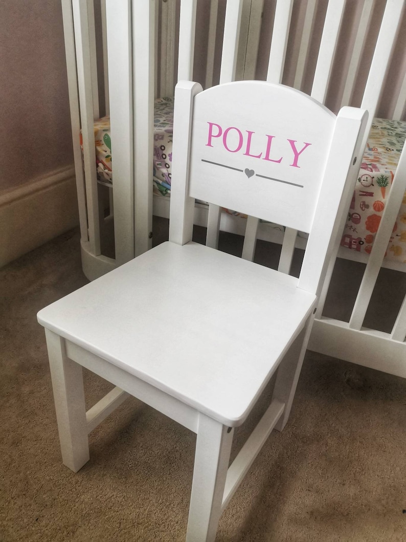 Pu&ograve; includere: Sedia di legno bianca per bambini con schienale arrotondato. Lo schienale della sedia &egrave; dipinto con il nome "POLLY" in lettere rosa con un cuore grigio sotto.