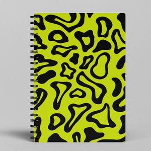 May include: A lime green spiral notebook with a black abstract pattern of irregular shapes.
