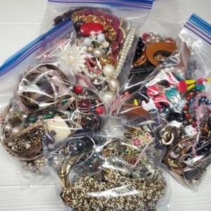 May include: Four clear plastic bags filled with a variety of colorful jewelry, including necklaces, bracelets, earrings, and charms. The jewelry is a mix of beads, metal, and plastic.