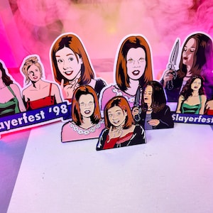 May include: A set of nine enamel pins featuring characters from the TV show Buffy the Vampire Slayer. The pins are colourful and feature different characters from the show, including Buffy Summers, Willow Rosenberg, and Cordelia Chase. The pins are all in a Slayerfest '98 theme.