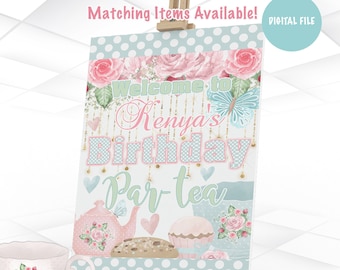 May include: A digital printable sign for a birthday party with a tea party theme. The sign is blue and white with pink flowers and a butterfly. The text on the sign reads "Welcome to Kenya's Birthday Par-tea".