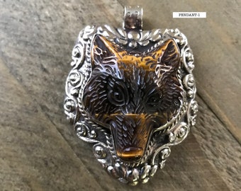 May include: A silver pendant with an ornate design features a wolf's head carved from tiger's eye stone. The pendant is labeled "PENDANT-1".