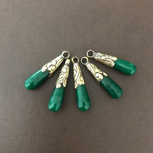 May include: Six green gemstone teardrop pendants with gold-toned metal accents. The pendants have a decorative, ornate design.