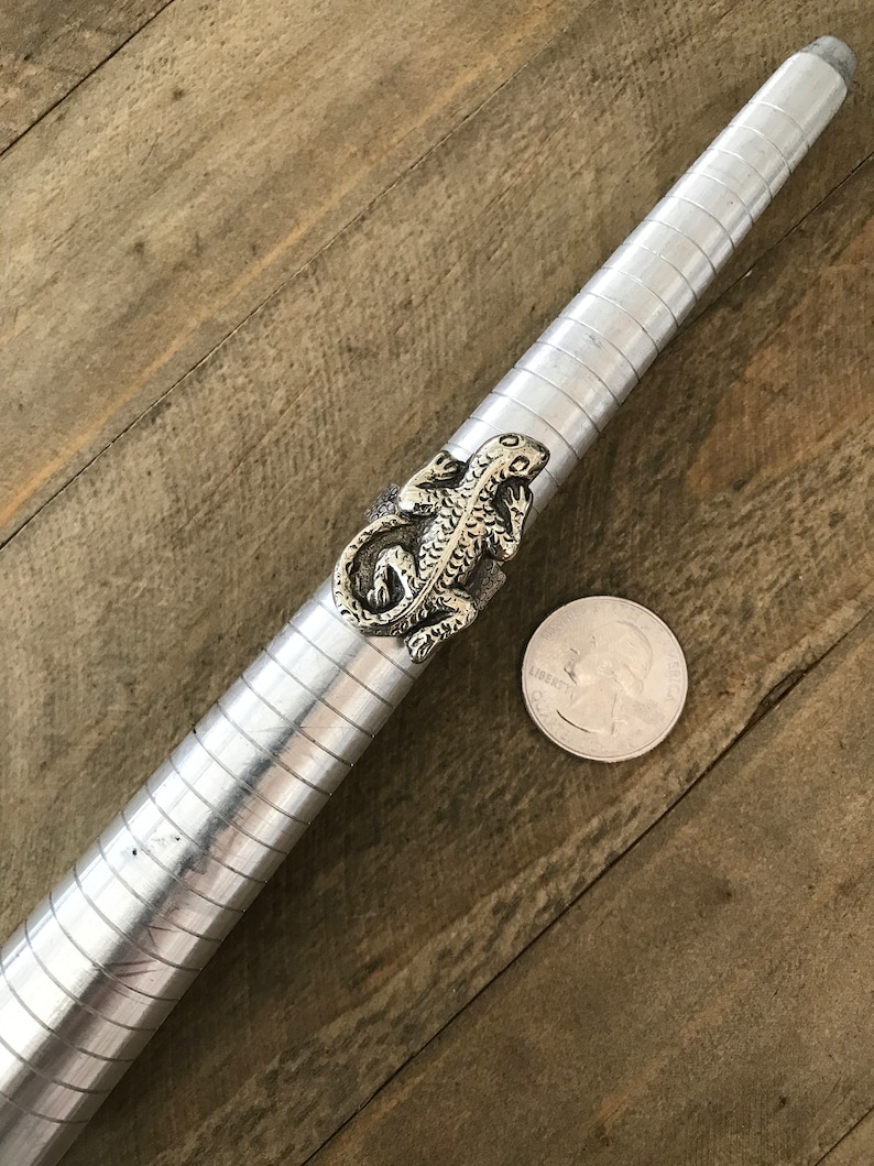 May include: A silver ring with a detailed lizard design. The ring is shown on a ring sizer with a US quarter for scale.