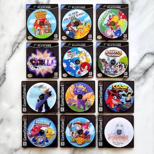May include: A collection of twelve video game discs in their cases. The discs feature colorful graphics and titles such as "Animal Town", "Super Brawl Bros", "Pickymin", "Majora", "Speed Heroes", "Harvest Season", "Final Fantasy VII", "Spyro", "Clash", "Digital World", "Black Cloud", and "dot.hacker".