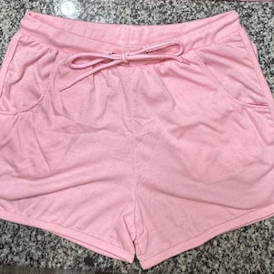 Könnte beinhalten: Rosa Shorts mit Kordelzug und Seitentaschen.