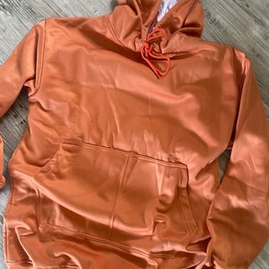 Op de afbeelding: Een roestkleurige hoodie met een capuchon met trekkoord en een zak aan de voorkant. De hoodie is gemaakt van een zachte, comfortabele stof.