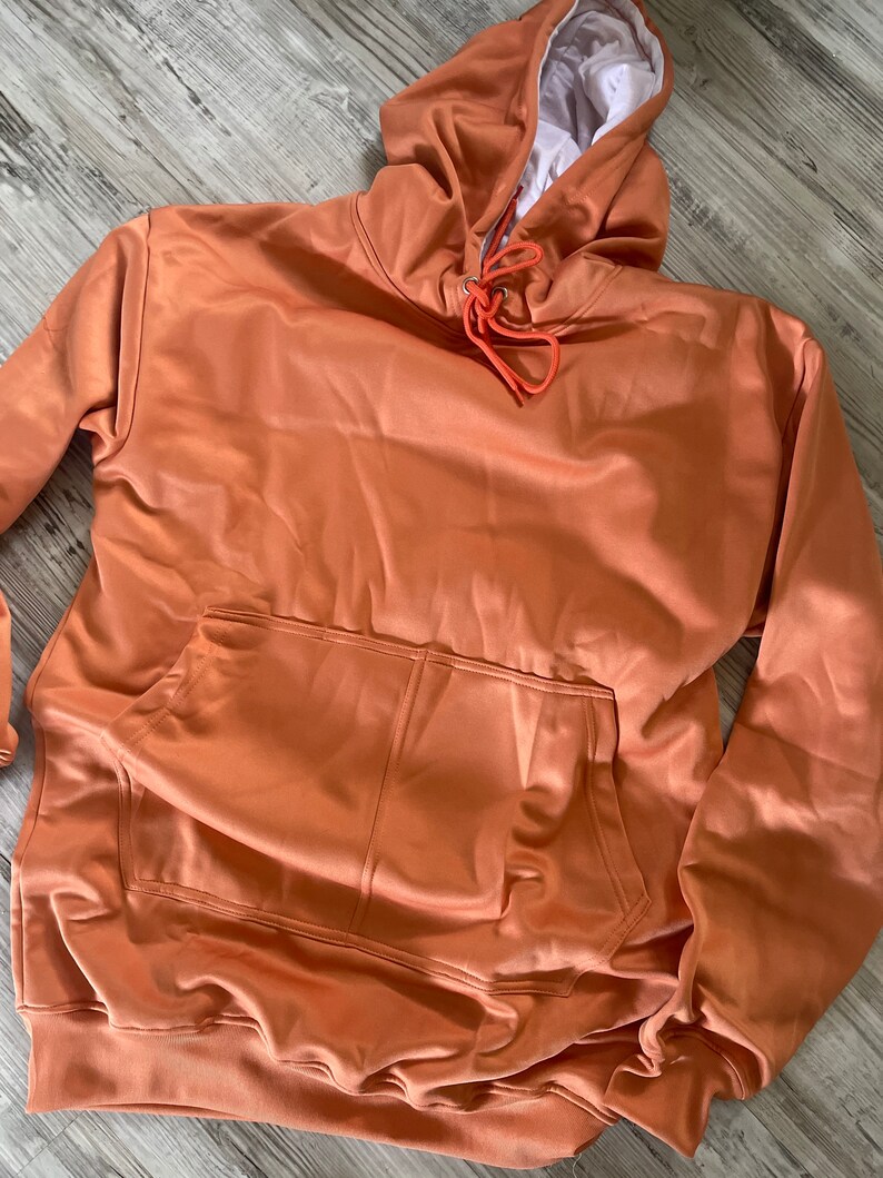Op de afbeelding: Een roestkleurige hoodie met een capuchon met trekkoord en een zak aan de voorkant. De hoodie is gemaakt van een zachte, comfortabele stof.