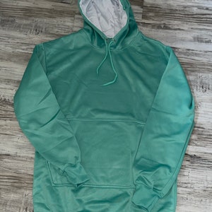 Op de afbeelding: Een lichtgroen hoodie met een witte capuchonvoering. De hoodie heeft een kangoeroezak en lange mouwen.