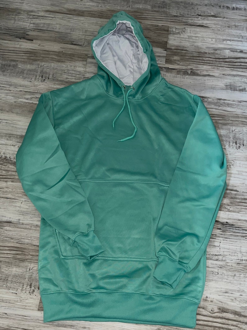 Op de afbeelding: Een lichtgroen hoodie met een witte capuchonvoering. De hoodie heeft een kangoeroezak en lange mouwen.