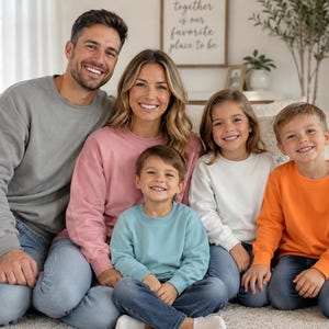 May include: A family of five wearing long-sleeved crewneck sweatshirts in various solid colors including gray, dusty rose, light blue, white, and bright orange, paired with blue denim jeans. Each sweatshirt features a simple, plain design.