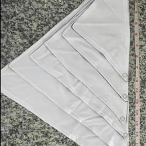 May include: A set of six white triangular fabric panels with grommets along the edges. The panels are arranged in a stack, with the largest panel at the bottom and the smallest panel at the top.