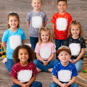 May include: A collection of seven short-sleeved crew neck t-shirts in various colors including blue, gray, red, pink, black, maroon, and royal blue. Each shirt features a bleached-style white rectangular patch on the front and is paired with blue jeans.