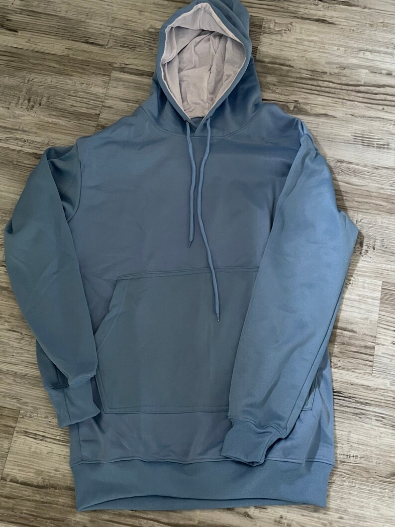 Op de afbeelding: Een lichtblauw hoodie met een zak en een capuchon met trekkoord.