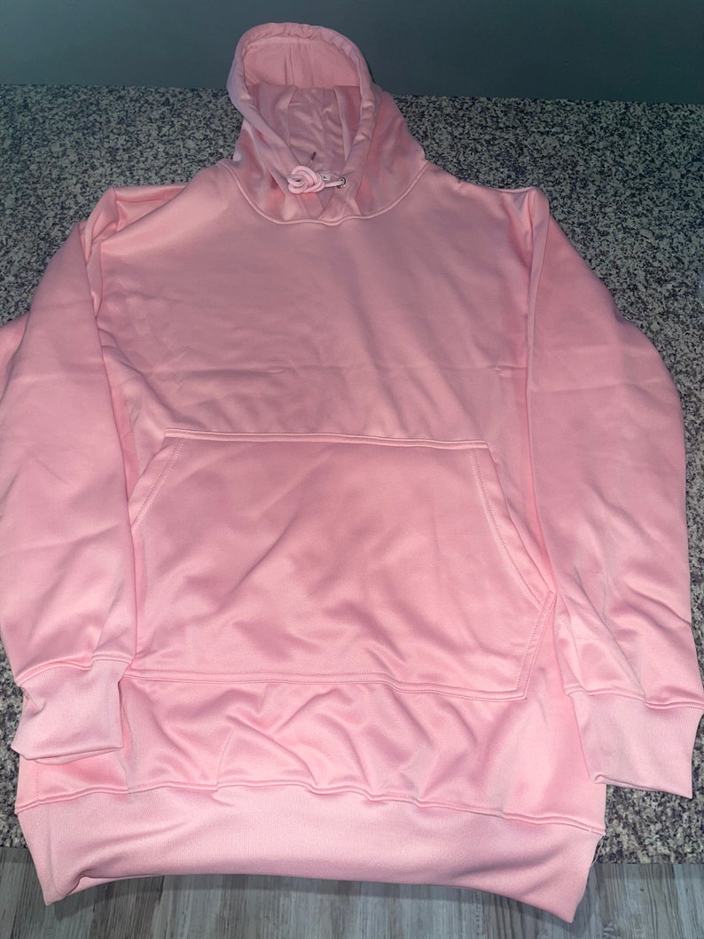 Op de afbeelding: Een lichtroze hoodie met een capuchon met trekkoord en een kangoeroezak.