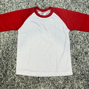 Könnte beinhalten: Ein weißes T-Shirt mit roten Raglanärmeln. Das Shirt hat einen Rundhalsausschnitt und ist aus weichem, bequemem Stoff.