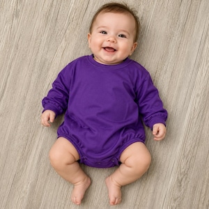 May include: A long-sleeved, solid purple baby romper featuring a crew neckline and gathered elastic cuffs at the wrists and leg openings. The garment is constructed with a simple, plain design and includes snap closures at the bottom for access.