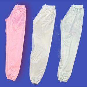 May include: Three pairs of sweatpants in different colors: pink, white, and light blue. The sweatpants are all made of a soft, comfortable fabric and have a relaxed fit.