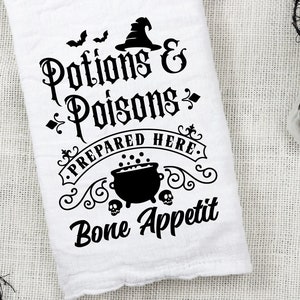 Könnte beinhalten: Ein weißes Küchentuch mit schwarzem Text, der "Tränke & Gifte Hier zubereitet. Guten Appetit" lautet. Der Text ist in gotischer Schrift und enthält einen Kessel mit Blasen und Schädeln.