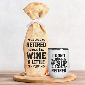 Könnte beinhalten: Ein weißer Weintumbler mit dem Text "Ich gebe keinen Schluck, ich bin im Ruhestand" und einer Weinglasgrafik. Neben dem Tumbler befindet sich eine Weintüte aus Jute mit dem Text "Im Ruhestand, Zeit zum Wein trinken, ein bisschen".