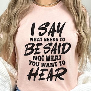 May include: A pink t-shirt with the text "I SAY WHAT NEEDS TO BE SAID NOT WHAT YOU WANT TO HEAR" in black.