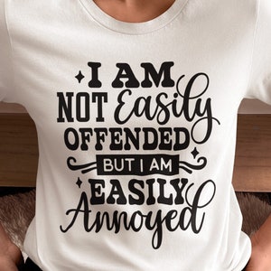 May include: A white t-shirt with black text that reads "I am not easily offended but I am easily annoyed".