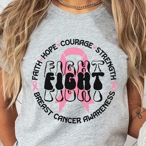 May include: A gray t-shirt with a pink ribbon and the words "Faith Hope Courage Strength" surrounding the word "FIGHT" in black, with the words "Breast Cancer Awareness" below.