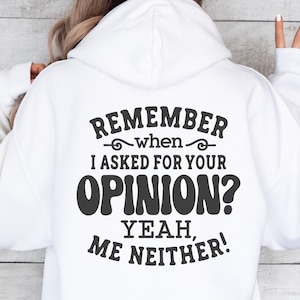 May include: White hoodie with black text that reads "Remember when I asked for your opinion? Yeah, me neither!"