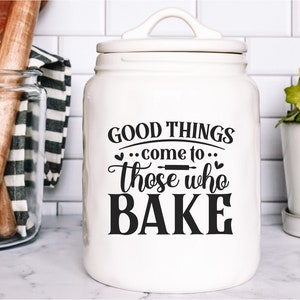 Könnte beinhalten: Eine weiße Keramikdose mit einer schwarzen Aufschrift, die lautet: "GOOD THINGS come to... those who BAKE".