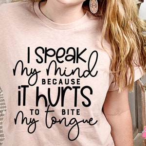 May include: A pink t-shirt with black text that reads "I speak my mind because it hurts to bite my tongue".