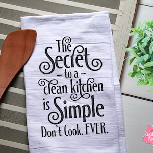 May include: White kitchen towel with black text that reads "The Secret to a clean kitchen is Simple Don't Cook. EVER."