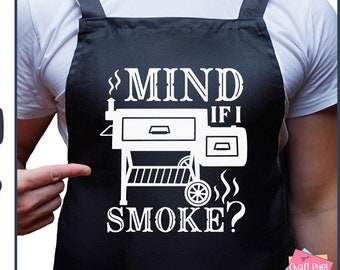 May include: Black apron with the text "MIND IF I SMOKE?" and a graphic of a smoker. The design is in white, with the text and smoker graphic. The apron is being pointed at by a person.