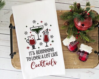 May include: White kitchen towel with a red and green Christmas design featuring three cocktail glasses and the text "It's beginning to look a lot like cocktails."