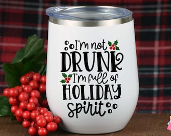 May include: White stainless steel tumbler with a black and green design that says "I'm not drunk I'm full of holiday spirit".
