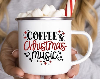 Könnte beinhalten: Eine weiße Emailletasse mit einem schwarzen und roten Design, auf dem "Coffee & Christmas Music" mit Noten und Sternen steht. Die Tasse ist mit Marshmallows und einem Zuckerstangen gefüllt.