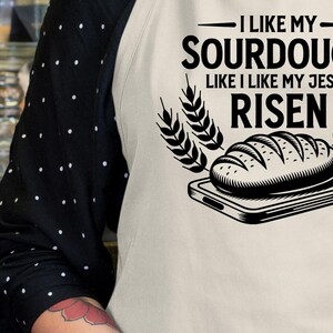 May include: Black and white graphic design of a sourdough bread loaf with the text "I like my sourdough like I like my Jesus risen".
