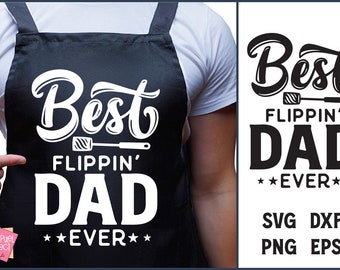 May include: Black apron with the text "Best Flippin' Dad Ever" in white. The design includes a spatula graphic. The apron is worn by a person wearing a white shirt. The image also shows the design as a digital file.