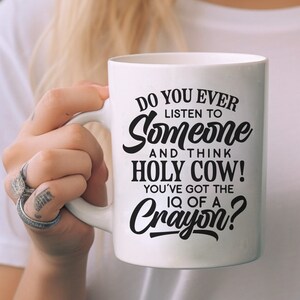 Może przedstawiać: Biały kubek ceramiczny z czarnym nadrukiem, na kt&oacute;rym widnieje napis "Do you ever listen to someone and think Holy Cow! You've got the IQ of a Crayon?"