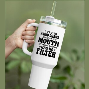 May include: White travel mug with a black handle and lid. The mug has a black graphic that reads "I try to avoid drama because the mouth my mama gave me >>has no<< filter".