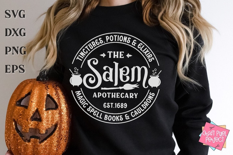 Pu&ograve; includere: Una felpa nera con un design circolare bianco che dice "The Salem Apothecary Est. 1689" con una scopa da strega, un calderone e il testo "Tinctures, Potions & Elixirs, Magic Spell Books & Cauldrons".