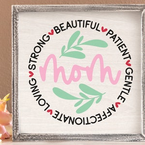 May include: A white sign with a pink circle in the center that says "Mom" in pink lettering.  The circle is surrounded by a black circle with the words "Affectionate, Loving, Strong, Beautiful, Patient, Gentle" in black lettering with red hearts between each word.