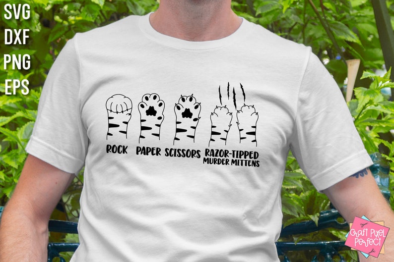 May include: A white t-shirt with a black graphic of a tiger paw print representing rock, paper, scissors, and razor-tipped murder mittens. The text "Rock Paper Scissors Razor-Tipped Murder Mittens" is printed below the graphic.