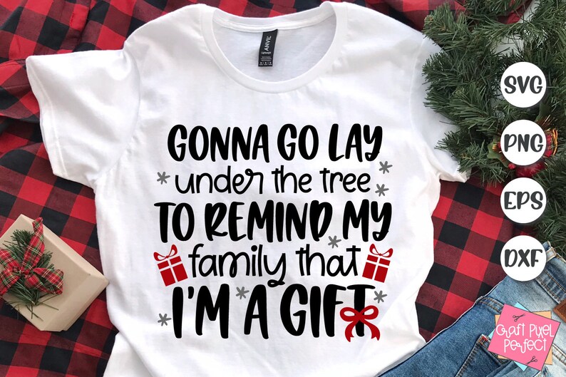 May include: White t-shirt with black text that reads "Gonna go lay under the tree to remind my family that I'm a gift". The text is surrounded by small red gift boxes and gray stars.