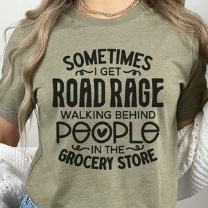 K&ouml;nnte beinhalten: Ein gr&uuml;nes T-Shirt mit dem Text "Sometimes I get road rage walking behind people in the grocery store" in Schwarz gedruckt.