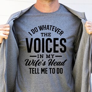 May include: A gray t-shirt with black text that reads "I do whatever the voices in my wife's head tell me to do".
