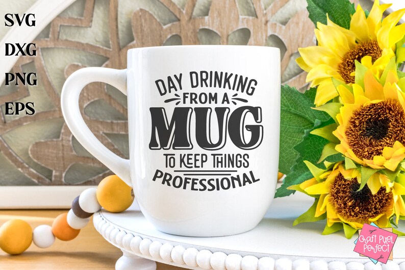 May include: White ceramic mug with black text that reads "Day Drinking From A Mug To Keep Things Professional". The mug is sitting on a white pedestal with a beaded garland and sunflowers in the background.