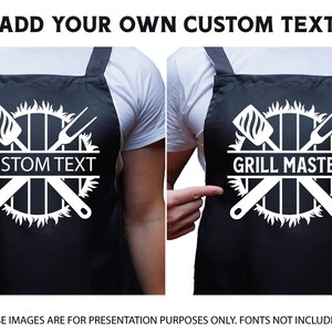 May include: Black apron with a white design of crossed grilling tools and flames around a grill grate. The text "CUSTOM TEXT" is in the center of the design.