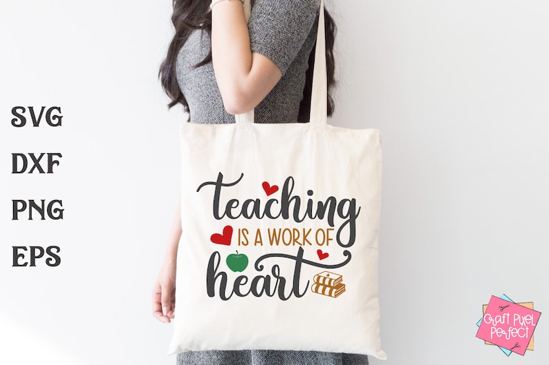 May include: A white tote bag with the text "teaching is a work of heart" in black. The text is surrounded by red hearts and a green apple. There are also two stacks of books in the design.