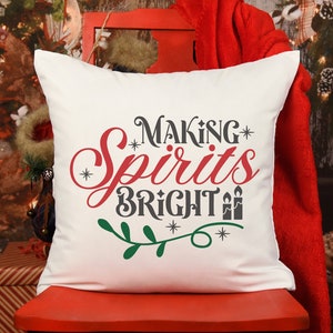 May include: White pillow with the text "Making Spirits Bright" in red, gray, and green lettering. The text is surrounded by a green leafy branch and small white stars.